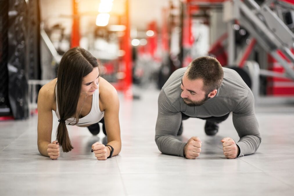 Bir erkek ve bir kadın, tüm kas grupları için tasarlanmış Plank egzersizini gerçekleştirir. 